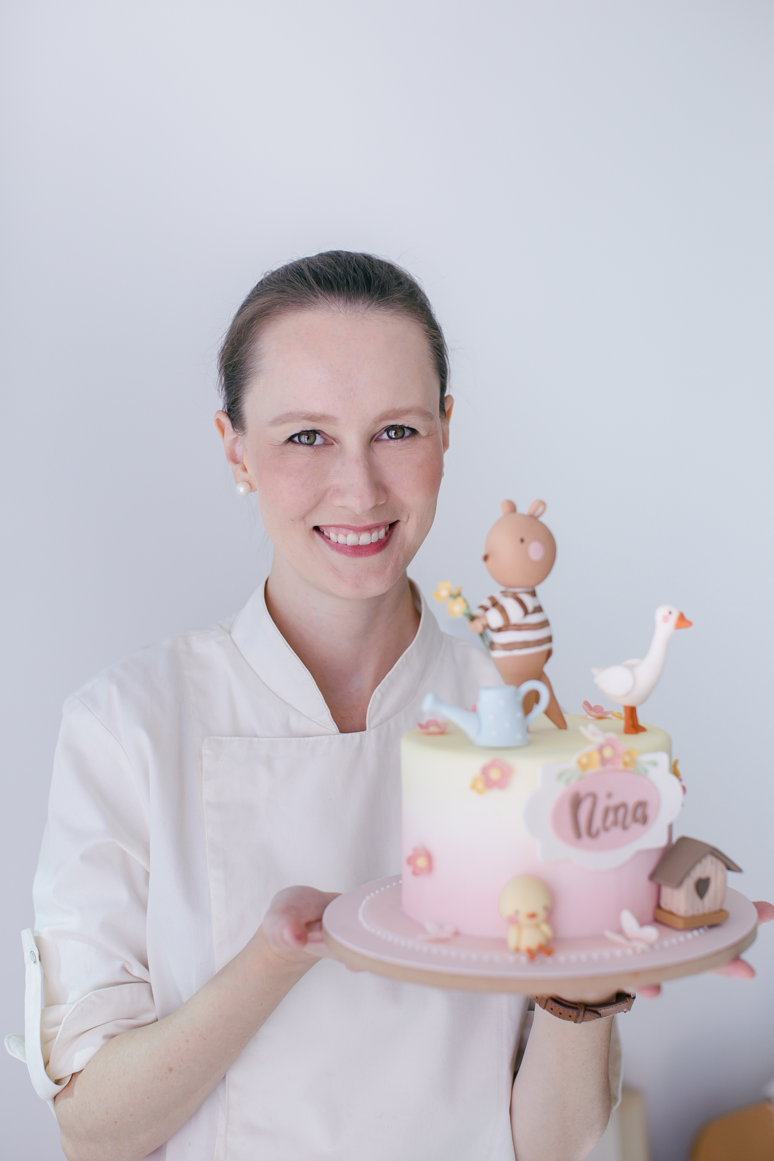 Chef Isa Herzog apresentando bolo decorado com animais em pasta americana